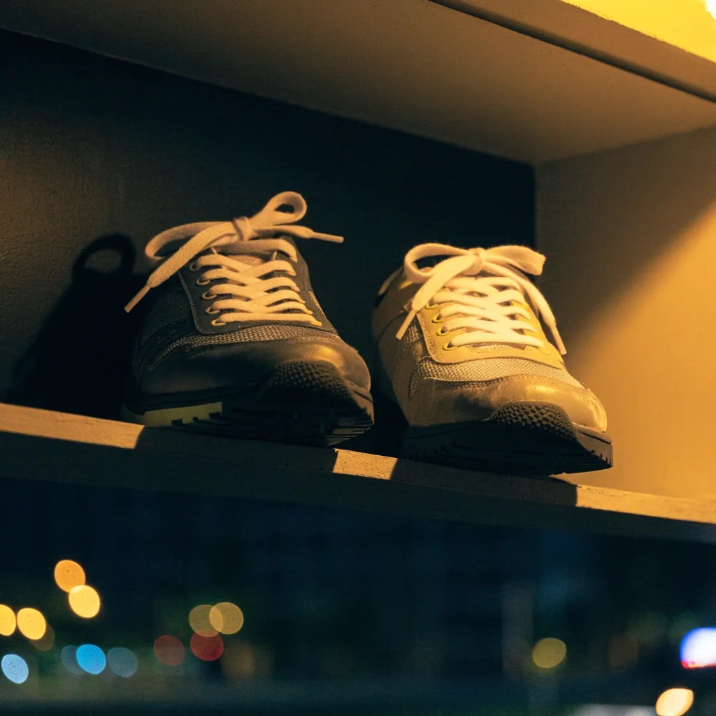 Deux sneakers urbaines basses côte à côte sur une étagère murale, vue de trois quarts